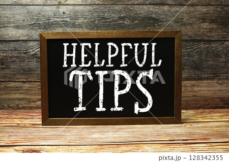 Helpful Tips text with blackboard on wooden background 128342355