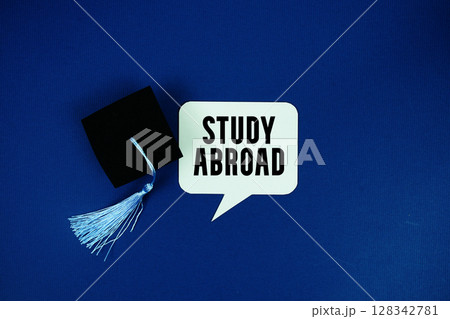 Study Abroad text on speech bubble with graduation cap top view on navy blue background 128342781