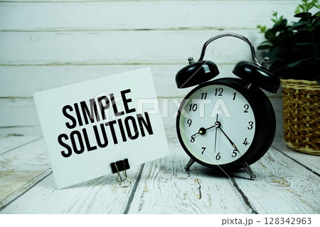 Simple Solution text on paper card with alarm clock on wooden background Simple Solution text on paper card with alarm clock on wooden background 128342963