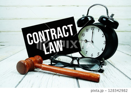 Contract Law text on paper card with alarm clock and wooden judge gavel on wooden background Contract Law text on paper card with alarm clock and wooden judge gavel on wooden background 128342982