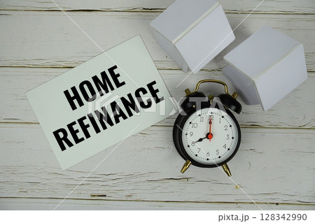 Home Refinance text message on paper card with alarm clcok and white house modelon wooden background 128342990