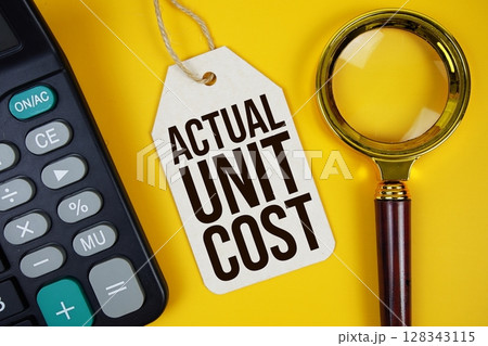 Actual Unit Cost text on price tag with magnifying glass and calculator on yellow background 128343115