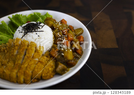 Fried Chicken Curry Rice On A Plate Placed On A Wooden Table, Background for advertising and wallpaper in culture and food scene. Fried Chicken Curry Rice On A Plate Placed On A Wooden Table, Background for advertising and wallpaper in culture and food scene. 128343189