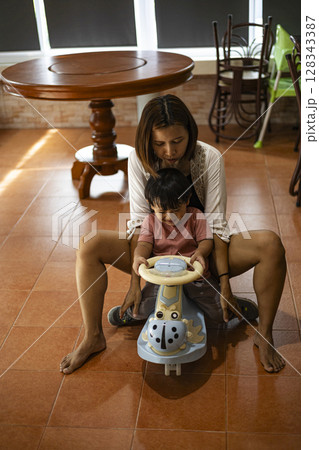 Mother And Toddler Riding A Toy Car In The House, Background for advertising and wallpaper in education and lifestyle scene. Mother And Toddler Riding A Toy Car In The House, Background for advertising and wallpaper in education and lifestyle scene. 128343387