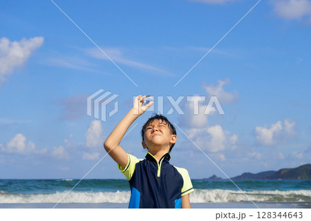 夏の浜辺で透明な球体を見つめる少年 夏の浜辺で透明な球体を見つめる少年 128344643