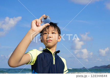 夏の浜辺で透明な球体を見つめる少年 夏の浜辺で透明な球体を見つめる少年 128344644