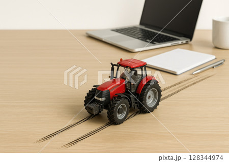 A red toy tractor is driving on the work table. A red toy tractor is driving on the work table. 128344974