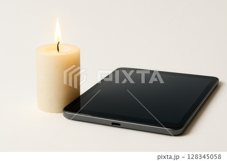 Candle and tablet on a light background. Space for text. Candle and tablet on a light background. Space for text. 128345058