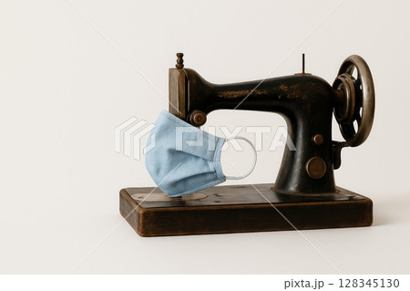 An old sewing machine and a mask, a symbol of the era. Space for text. 128345130