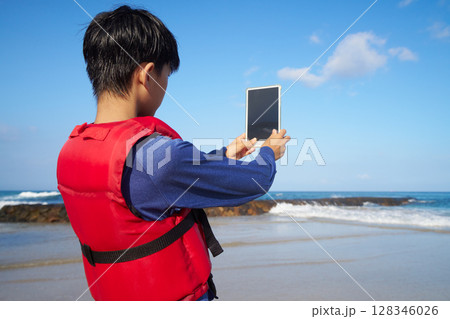 夏の砂浜でタブレットを持つ小学生 128346026