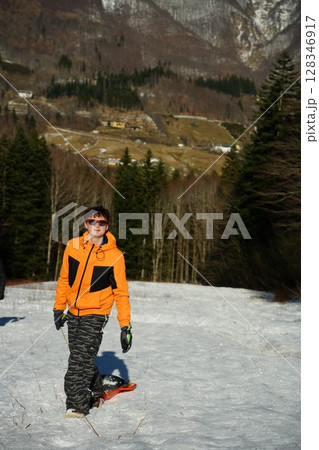 Teen in Bright Jacket Pulls Sled in Snowy Mountain Area 128346917