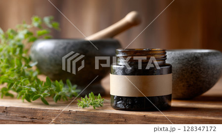 Herbal remedy jar with shilajit and mortar on wooden table surrounded by fresh herbs and natural elements 128347172