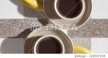 Two elegant coffee cups placed on a textured surface beside ripe bananas, showcasing a delightful morning beverage experience Two elegant coffee cups placed on a textured surface beside ripe bananas, showcasing a delightful morning beverage experience 128347244
