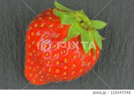 Macro shot of a ripe red strawberry on a black background. Ripe strawberry on a black slate backdrop. Close-up and top view Macro shot of a ripe red strawberry on a black background. Ripe strawberry on a black slate backdrop. Close-up and top view 128347348