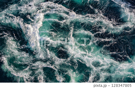 Blue waves of water of the river and the sea meet each other during high tide and low tide. 128347805