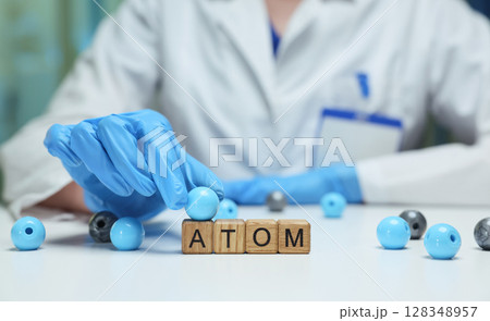 A scientist is meticulously examining atoms within a controlled laboratory environment A scientist is meticulously examining atoms within a controlled laboratory environment 128348957