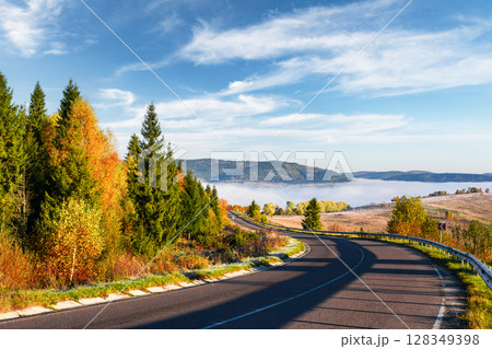 Calm landscape with autumn road and orange forest under blue sky Calm landscape with autumn road and orange forest under blue sky 128349398