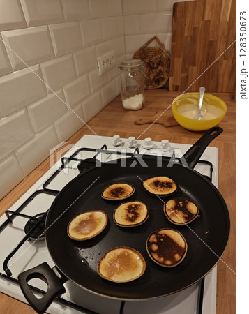 Perfectly golden pancakes sizzling on the stovetop in a cozy kitchen setting filled with warmth and delicious aromas Perfectly golden pancakes sizzling on the stovetop in a cozy kitchen setting filled with warmth and delicious aromas 128350673