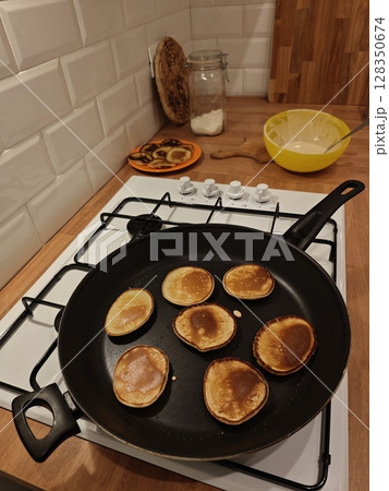 Fluffy pancakes sizzling on the stovetop in a cozy kitchen setting during a weekend morning Fluffy pancakes sizzling on the stovetop in a cozy kitchen setting during a weekend morning 128350674