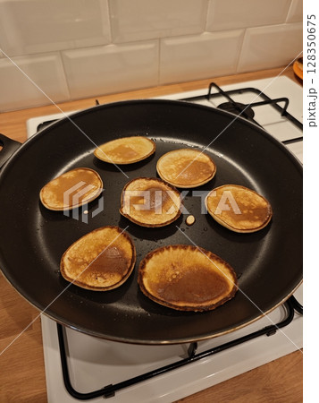 Fluffy pancakes sizzle in a warm skillet on a cozy kitchen stove during a delightful breakfast morning Fluffy pancakes sizzle in a warm skillet on a cozy kitchen stove during a delightful breakfast morning 128350675