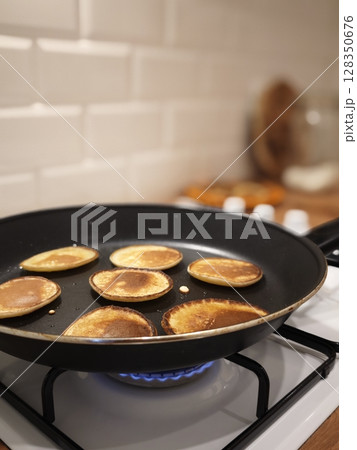 Fluffy golden pancakes cooking on a modern stovetop in a cozy kitchen atmosphere 128350676