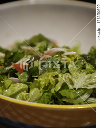 Freshly prepared garden salad featuring vibrant greens and seasonal vegetables in a cheerful bowl during a cozy dinner gathering 128350699