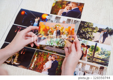 hands with photos and Printed wedding photos laid out on a wooden surface. 128350744