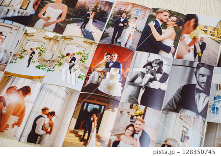 Printed wedding photos laid out on a wooden surface. 128350745
