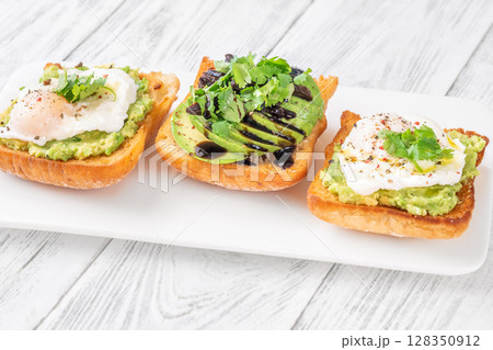 Ciabatta sandwiches with poached egg, avocado mash, sundried tomato and herbs 128350912