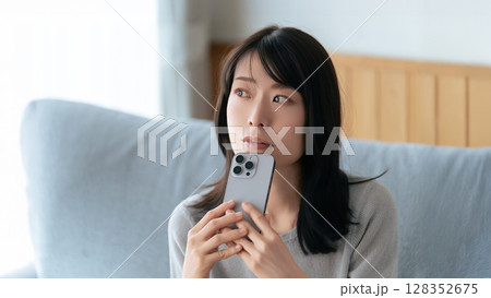スマートフォンを持って考える女性 スマートフォンを持って考える女性 128352675