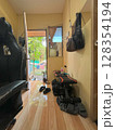 Indoor room with a cat looking out an open door, home gym equipment, and a gaming chair. 128354194