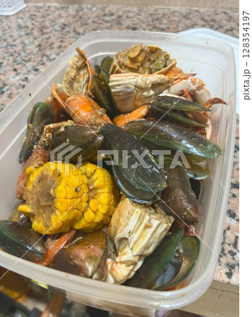 Close-up of a flavorful seafood boil featuring crab, mussels, shrimp, and corn on the cob. Close-up of a flavorful seafood boil featuring crab, mussels, shrimp, and corn on the cob. 128354197
