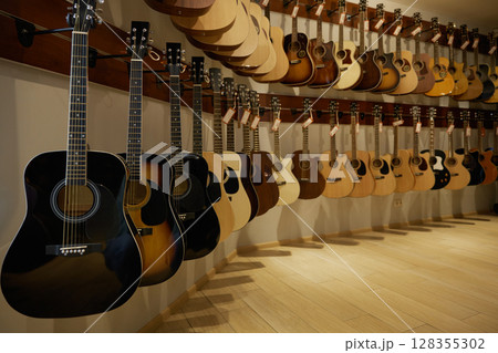 A large assortment of guitars is beautifully hanging on a wall 128355302