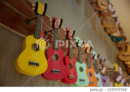 A beautiful row of colorful ukulele guitars is hanging on a wall A beautiful row of colorful ukulele guitars is hanging on a wall 128355308