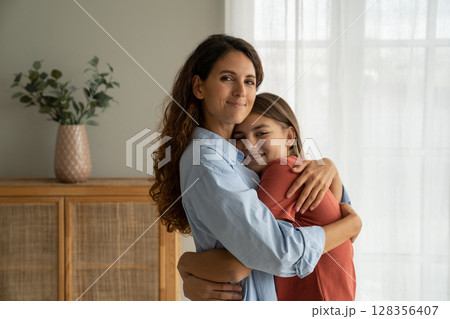 Kind optimistic Spanish woman hugging smiling teenage girl accepting congratulations on mother day Kind optimistic Spanish woman hugging smiling teenage girl accepting congratulations on mother day 128356407