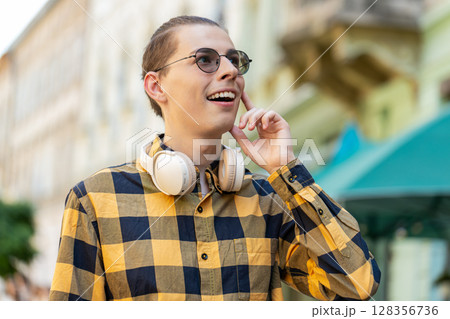 Happy smiling Caucasian young man tourist enjoying walking in urban city street positive good mood 128356736