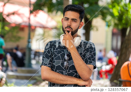 Thoughtful pensive puzzled Indian man with pensive expression pondering a solution doubting question 128357067