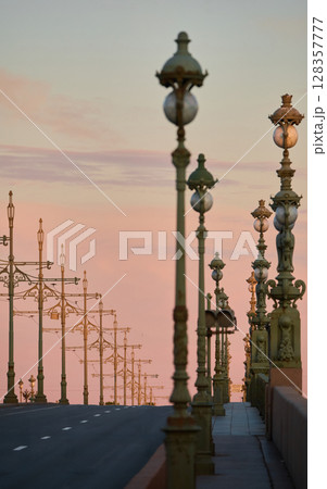 rows of lampposts and poles with electric grids for a tram on an empty Troitskiy Bridge at a pink sunset, nobody rows of lampposts and poles with electric grids for a tram on an empty Troitskiy Bridge at a pink sunset, nobody 128357777
