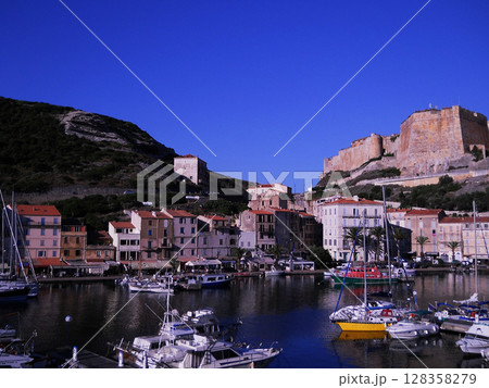 Scenic View of Bonifacio Port in Corsica with Luxury Yachts and Cliffside Town Experience the charm of the French island of Corsica with this stunning image capturing the picturesque port of Bonifacio 128358279