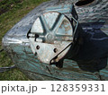 A close-up view of a worn machinery component revealing rust and corrosion. The part is situated on a metallic surface in a grassy outdoor area, reflecting age and usage. 128359331