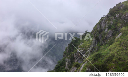 Misty Mountain Landscape with Lush Greenery and Rocky Cliffs Misty Mountain Landscape with Lush Greenery and Rocky Cliffs 128359602