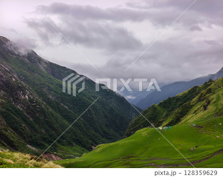 Cloudy Mountain Vista with Lush Green Slopes 128359629