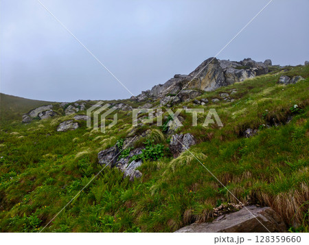 Rocky Green Hillside with Scenic Cliff View Under Overcast Sky 128359660