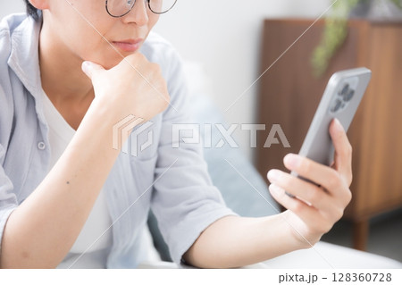 スマホを見る、持つ考える悩むの眼鏡の男性のクローズアップ　顔無し	 128360728