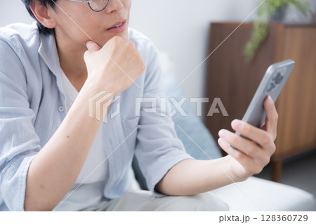 スマホを見る、持つ考える悩むの眼鏡の男性のクローズアップ 顔無し スマホを見る、持つ考える悩むの眼鏡の男性のクローズアップ 顔無し 128360729