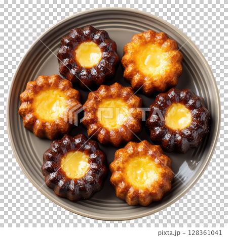 Small French Pastries Caneles de Bordeaux with Soft Custard Center and Dark Caramelized Crust on Plate 128361041
