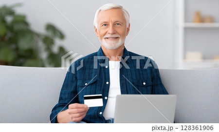 Social security benefits concept, A senior man holding a credit card while using a laptop at home. 128361906