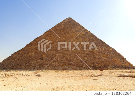 Majestic pyramid stands tall under bright sky at Giza, showcasing ancient Egyptian architecture and history Majestic pyramid stands tall under bright sky at Giza, showcasing ancient Egyptian architecture and history 128362264