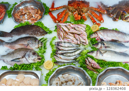 Fresh seafood display with various fish and shellfish on ice at a market Fresh seafood display with various fish and shellfish on ice at a market 128362408