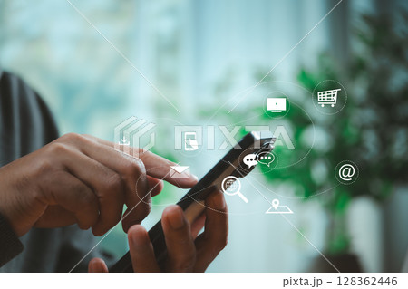 Person using smartphone with floating digital app icons representing cloud services, messaging, shopping, and online business technology in modern lifestyle. 128362446